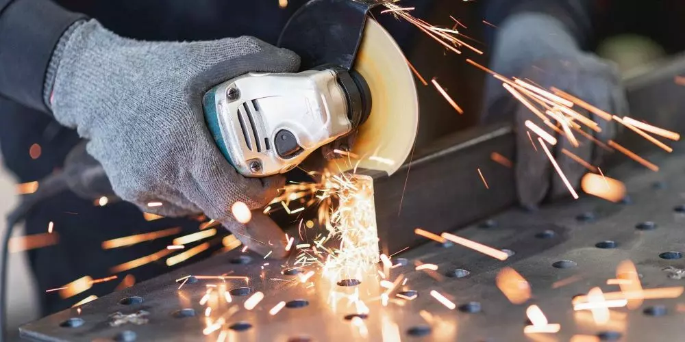 An angle grinder cutting through a metal pipe