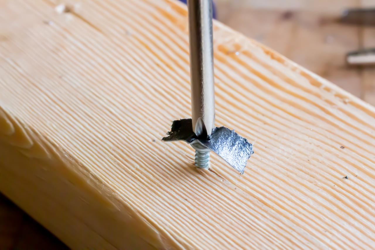A screwdriver in a stripped screw hole in a piece of wood